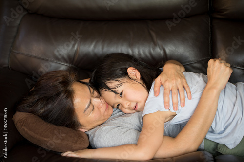 Asian mother and daughter hugging on sofa
