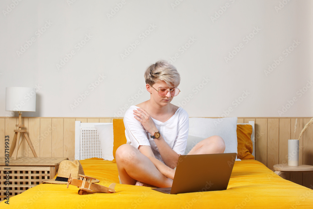 Full body of bright trendy female browsing in laptop, booking and researching travel