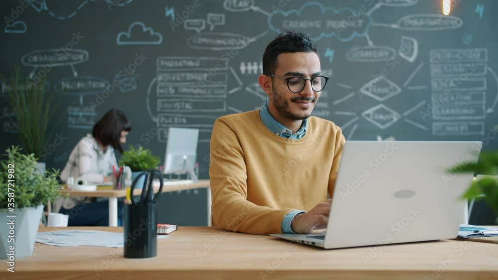 Portrait of Afro-American man working with laptop in open space office typing enjoying job. Coworking, young people and modern technology concept. Portrait of Afro-American man working with laptop in open space office typing enjoying job. Coworking, young people and modern technology concept.