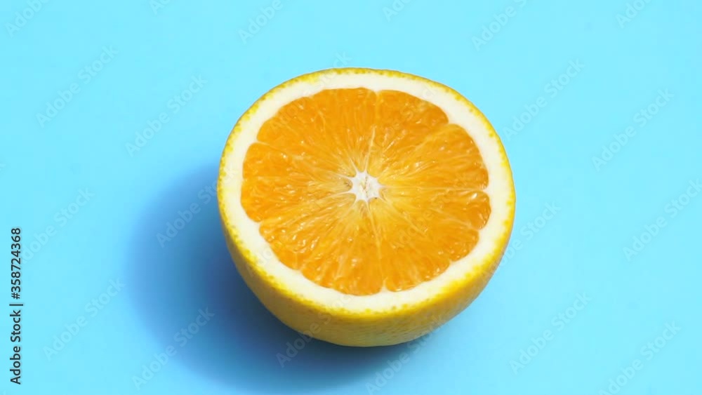 Rotating orange on a blue background isolate. Juicy fresh yellow orange in the summer sunlight on a colored pastel background. Fresh juices, fruits, vitamin and summer concept. Rotating orange on a blue background isolate. Juicy fresh yellow orange in the summer sunlight on a colored pastel background. Fresh juices, fruits, vitamin and summer concept.