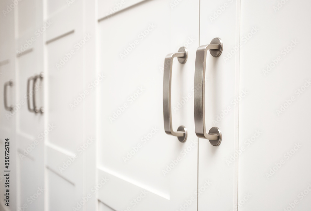 White wooden cupboard doors modern interior, storage or wardrobe closed with metal handles White wooden cupboard doors modern interior, storage or wardrobe closed with metal handles