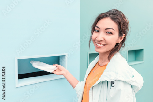 smiling girl passes a plastic bottle for recycling at the waste collection point. The concept of environmental awareness in the younger generation.