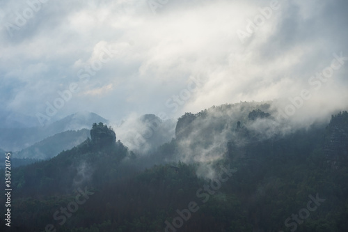 Dramatic foggy landscape with clouds in the morning in Saxon Switzerland, Germany