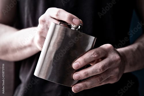 Young man holding a stainless steele Hip Flask with liquor, alcohol and booze concept photo
