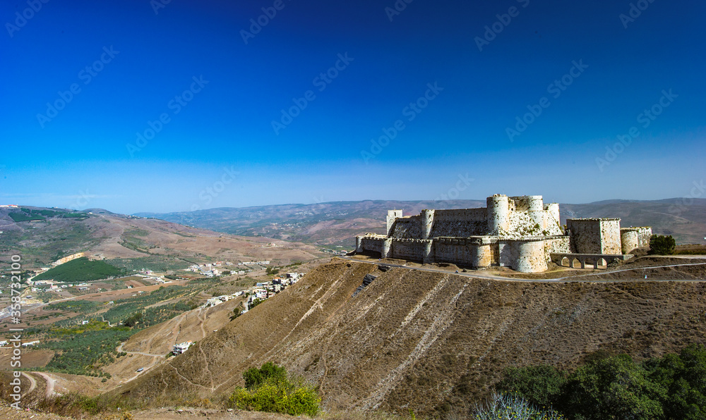 It's Krak des Chevaliers, also Crac des Chevaliers, is a Crusader castle in Syria and one of the most important preserved medieval castles in the world. - obrazy, fototapety, plakaty 