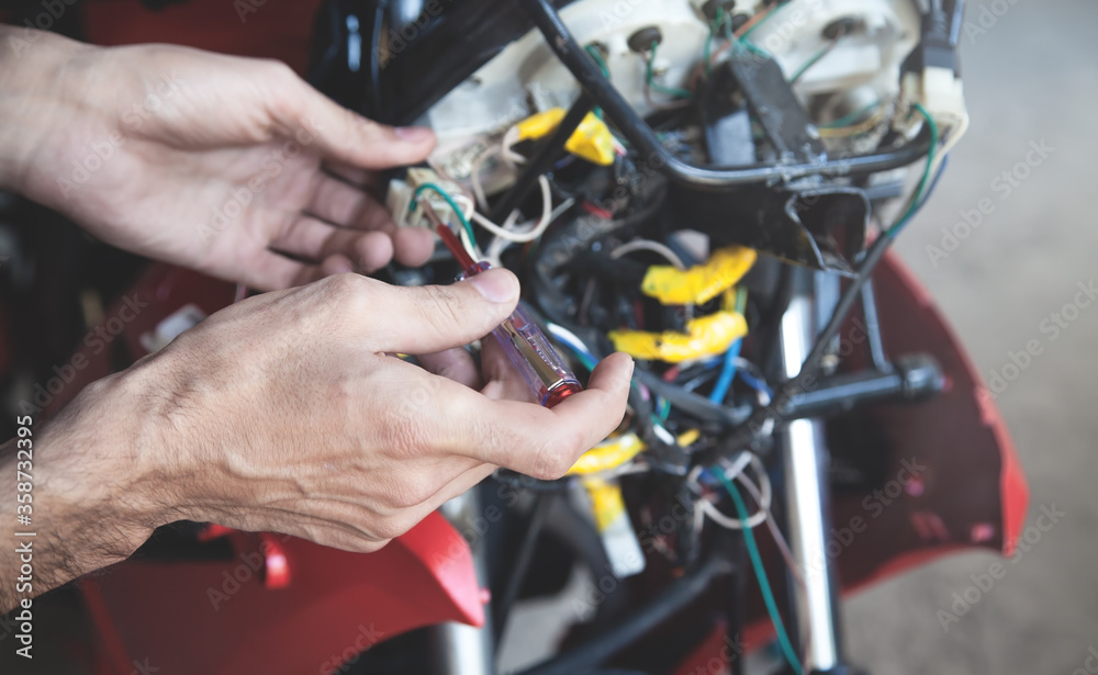 Obraz premium Mechanic man wiring the electrical cables motorcycle.