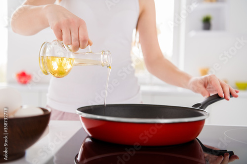 Cropped close up photo of chef woman frying pan olive oil prepare tasty ecological supper on stove in kitchen house indoors