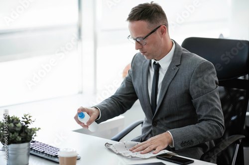 Foto Handsome businessman disinfecting desk in the office.