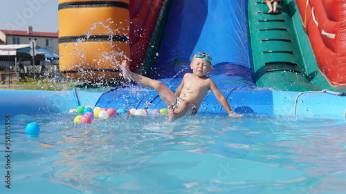 Child jump on inflatable water slide. Aqua amusement park of sea resort.