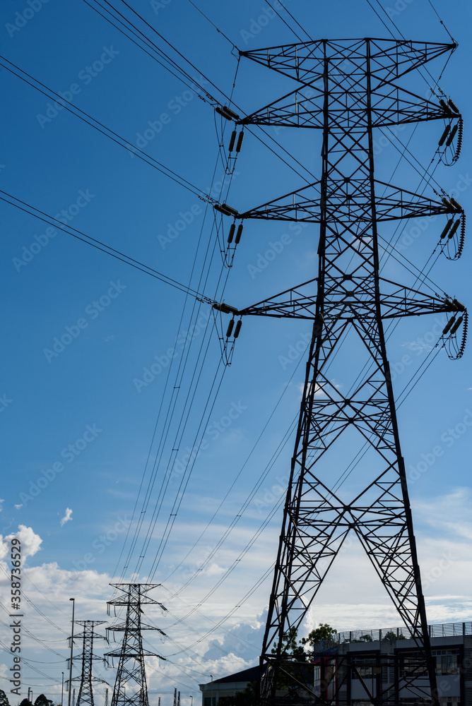 Kuching, Sarawak / Malaysia - August 28, 2017: Power poles and cables silhouetted in blue sky.