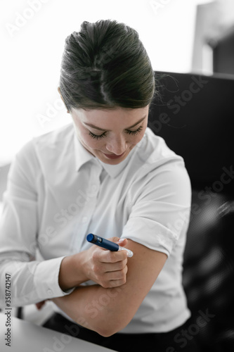 Businesswoman giving herself an injection of insulin. 