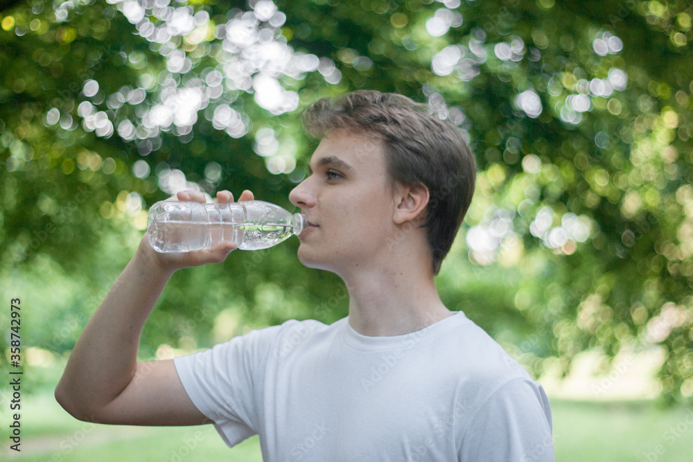 A young man drinks clean cool water from a plastic bottle A young man drinks clean cool water from a plastic bottle