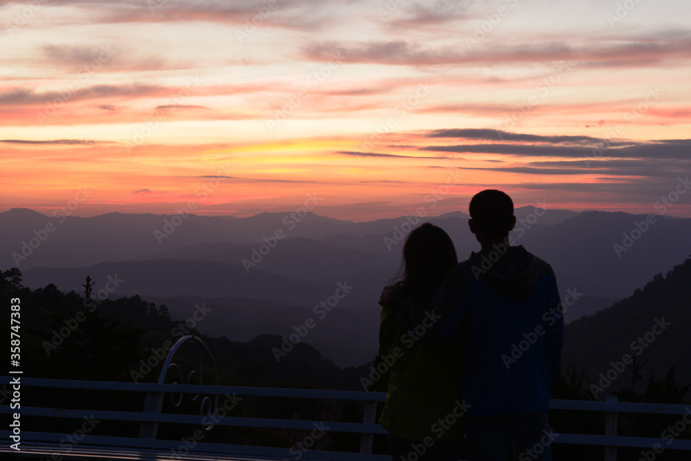 silhouette of a man with his lover is waiting for Amazing twilight over the mountain at Doi Inthanond national park. Chiang Mai, Thailand.