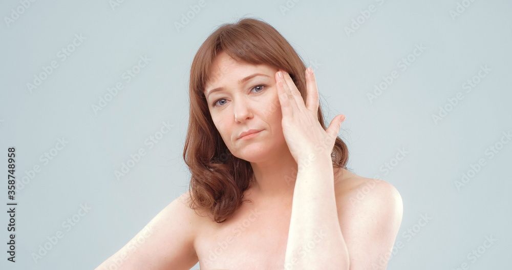 Mature naked woman feels headache. Serious red haired lady touches her head with hand. Skin care concept. Mature naked woman feels headache. Serious red haired lady touches her head with hand. Skin care concept.