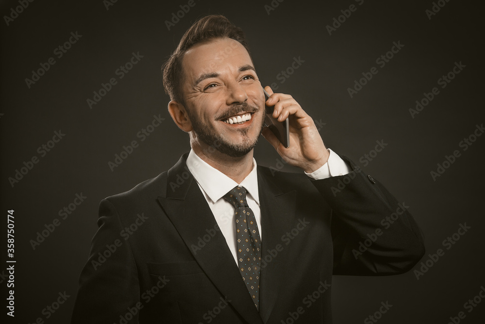 Cheerful businessman broadly smiles talking on mobile phone. Portrait of busy office worker using cellphone. Communication wireless concept. Tinted image. Cheerful businessman broadly smiles talking on mobile phone. Portrait of busy office worker using cellphone. Communication wireless concept. Tinted image.