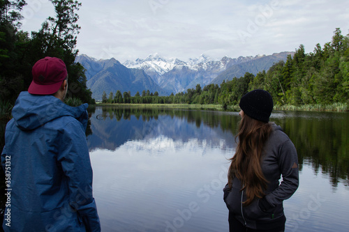 Couple looking over the Lake Matheson in New Zealand South Island. June ‎12, ‎2018