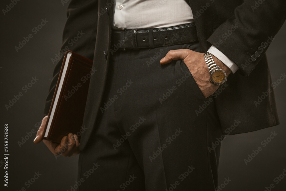 Businessman holds folder with documents in one hand and keeps other hand in his pocket. Close up shot. Tinted image.