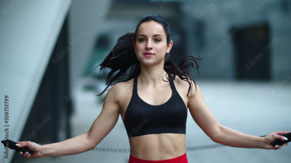 Fit woman jumping with skipping rope outdoor. Athlete woman practicing jumping