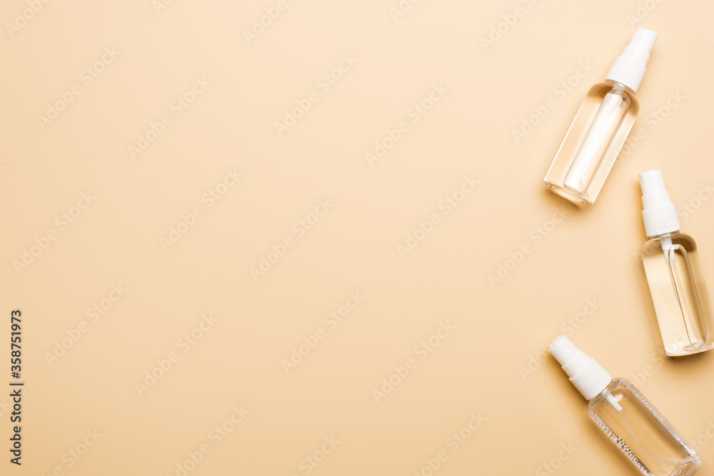 top view of transparent spray bottles with liquid disifectant on beige top view of transparent spray bottles with liquid disifectant on beige