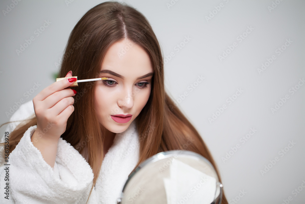 Beauty makeup, young woman with beautiful skin holding eyelash brush near eyes Beauty makeup, young woman with beautiful skin holding eyelash brush near eyes