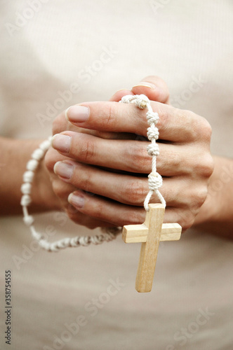 Hands of adult woman praying with a rosary