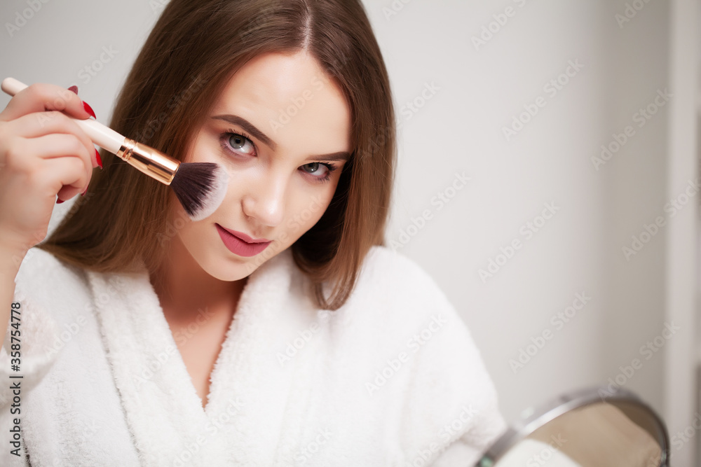 Beauty makeup, young woman with clean skin holds brush for applying makeup near her face