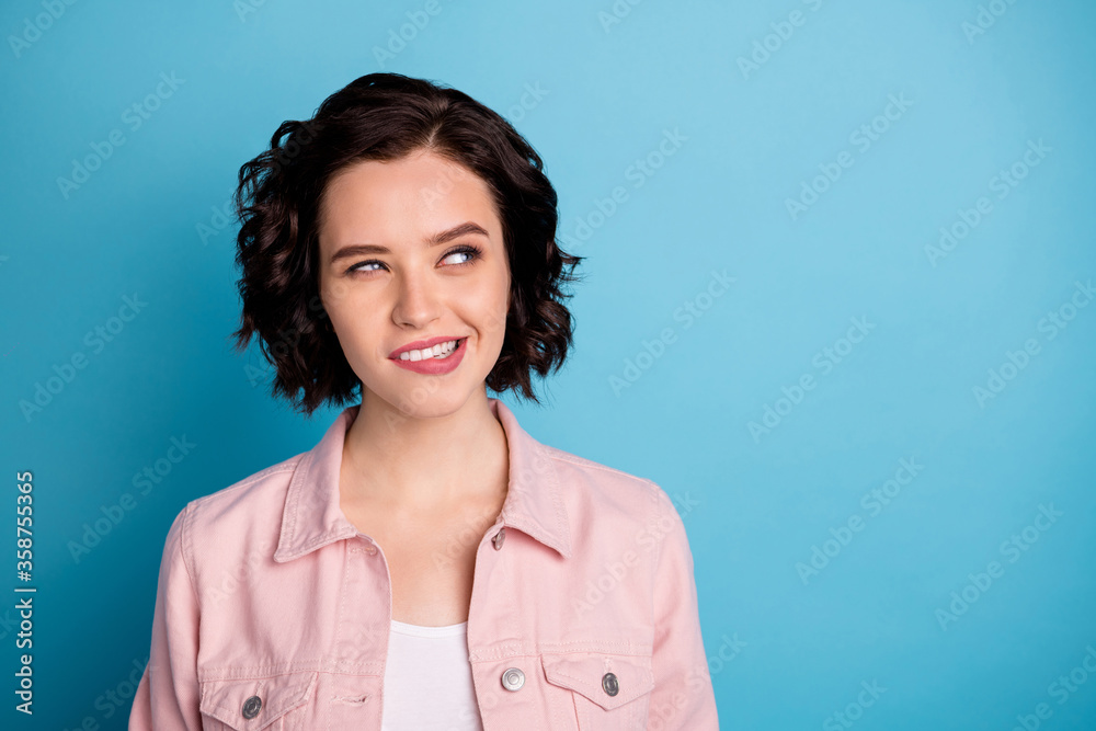 Closeup photo of attractive interested lady groomed short black hairdo look side empty space biting lips wondered wear casual pink denim jacket isolated blue color background Closeup photo of attractive interested lady groomed short black hairdo look side empty space biting lips wondered wear casual pink denim jacket isolated blue color background