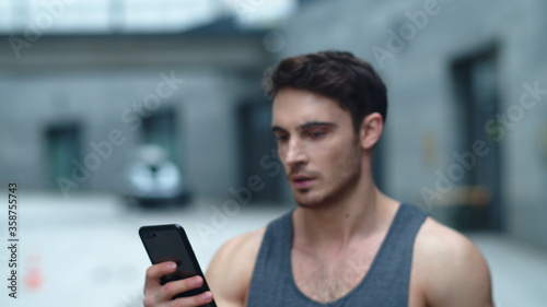 Closeup athlete man looking smartphone on street. Smiling man reading message