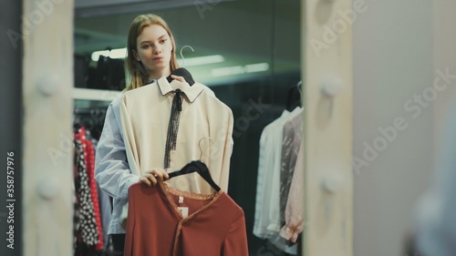 Attractive female customer is trying on blouse in fitting room