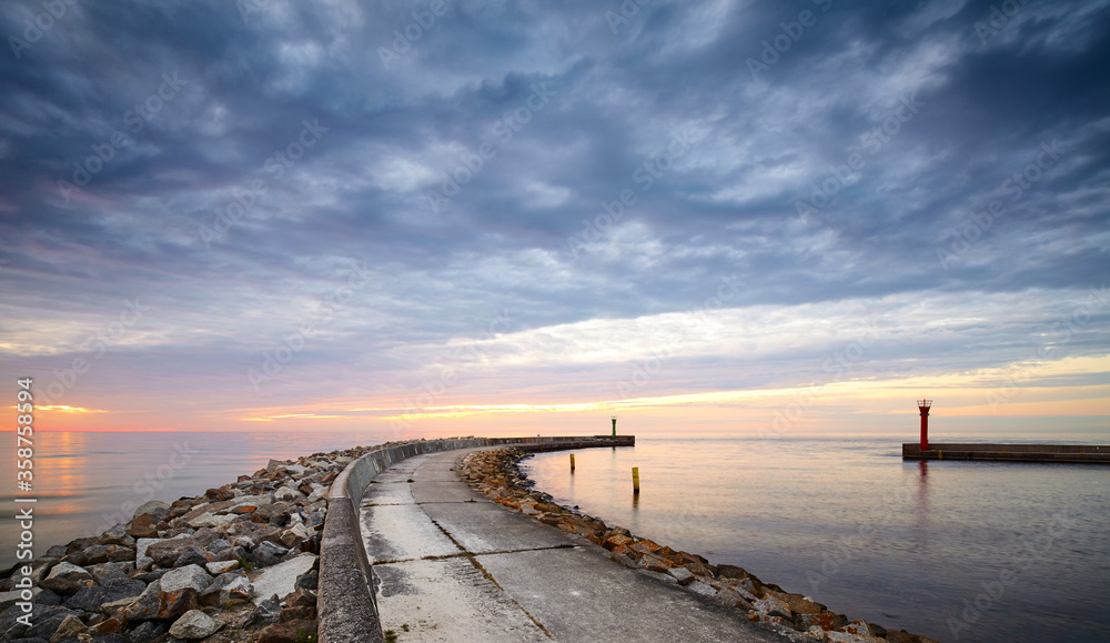 Panoramic view of rocky pier at the entrance to the harbor at sunset.