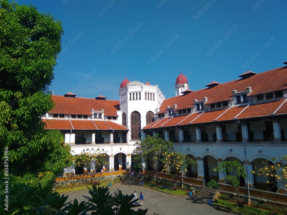 An old white building that stands majestically in the `Lawang Sewu` tour in the city of Semarang with a very thick and green banyan tree