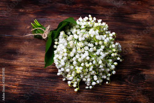 Delicate bouquet of lily of the valley on a wooden table. Bouquet for the holiday. Selective focus.