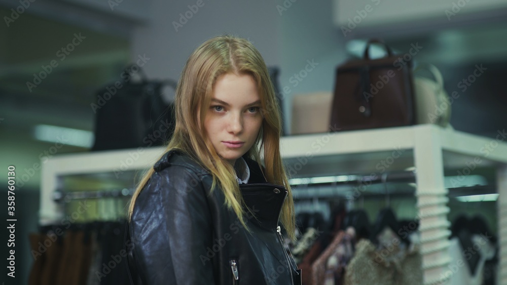 Young beautiful girl trying on a leather jacket in the store. Young beautiful girl trying on a leather jacket in the store.