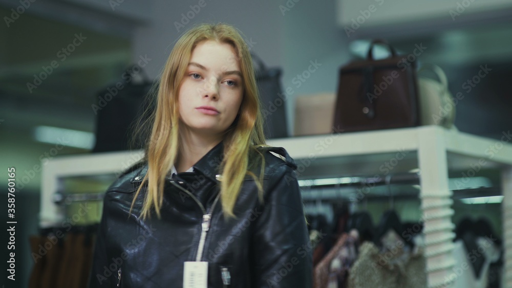Young beautiful girl trying on a leather jacket in the store.