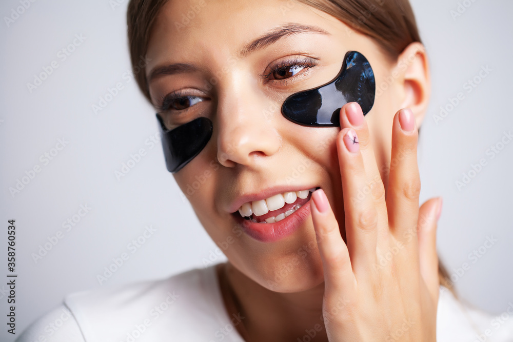 Beauty care, young beautiful woman with black patches for skin care under the eyes Beauty care, young beautiful woman with black patches for skin care under the eyes