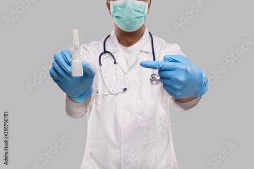 Doctor Pointing at Nose Spray Wearing Medical Mask and Gloves Close Up. Indian Man Doctor Nasal Spray. Corona Virus Concept. Isolated