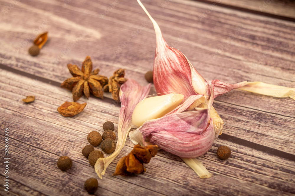 Garlic cloves, star anise, allspice on a wooden table. Close up. Garlic cloves, star anise, allspice on a wooden table. Close up.
