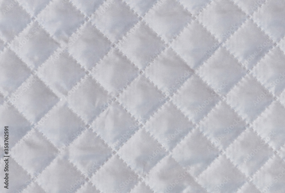 Fototapeta premium Checkered texture of white fabric with diagonal mesh embossing. Abstract material pattern or background. Close up shot.