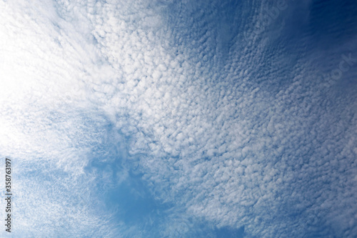 Blue sky covered with white cirrus clouds. Summer cloudscape, beautiful weather background