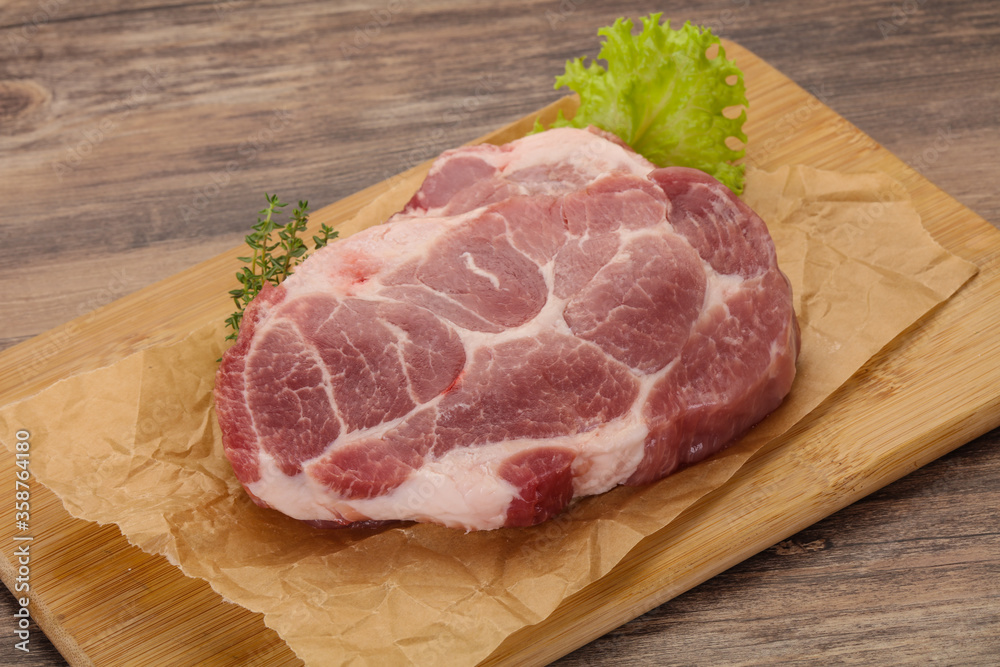 Raw pork steak over wooden board