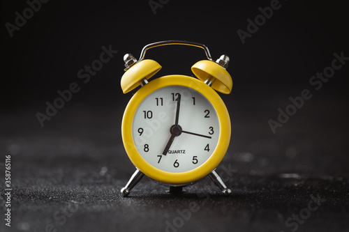 Yellow vintage alarm clock on the black background. shallow depth of field
