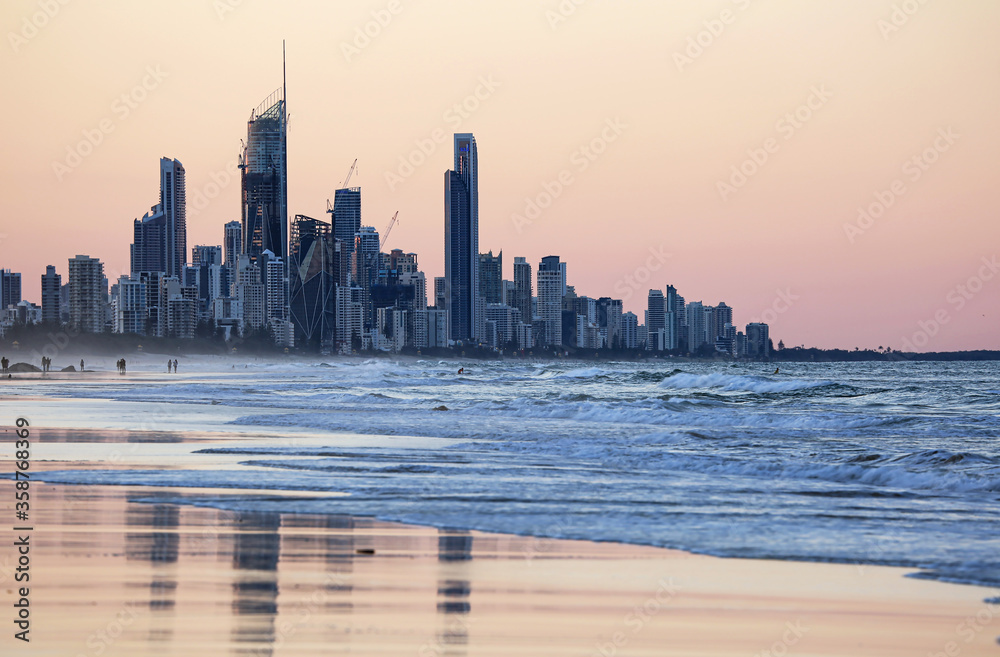 Sweeping view of the Surfers Paradise skyscrapers at sunset  reflected in the wet sands of the Pacific Ocean - Queensland, Australia.