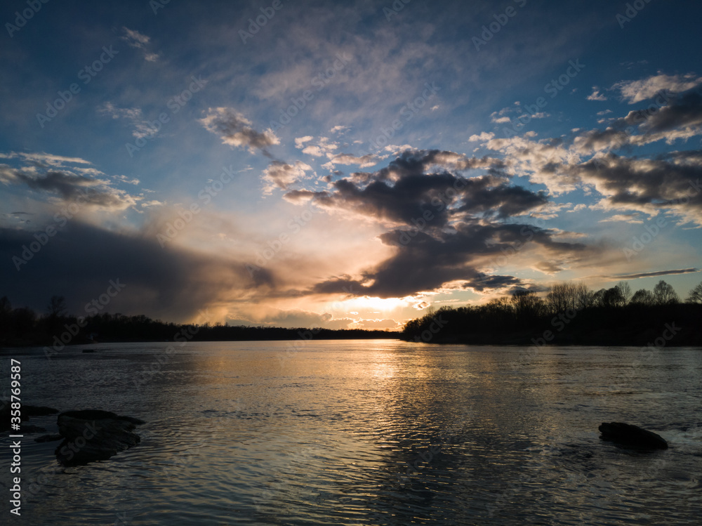 Fototapeta premium Beautiful sunset landscape by the river with a rocky shore.