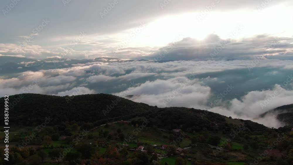 Overhead flight above beautiful residential buildings in village on mountain plateau with epic scenic views of cloudscape bright white light from sun, aerial Overhead flight above beautiful residential buildings in village on mountain plateau with epic scenic views of cloudscape bright white light from sun, aerial