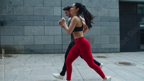 Sport couple running outdoor in slow motion. Young man and woman training run photo