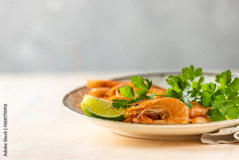 Beautiful boiled large shrimp in light ceramic plate with parsley and lime on pink concrete table surface. Beautiful boiled large shrimp in light ceramic plate with parsley and lime on pink concrete table surface.