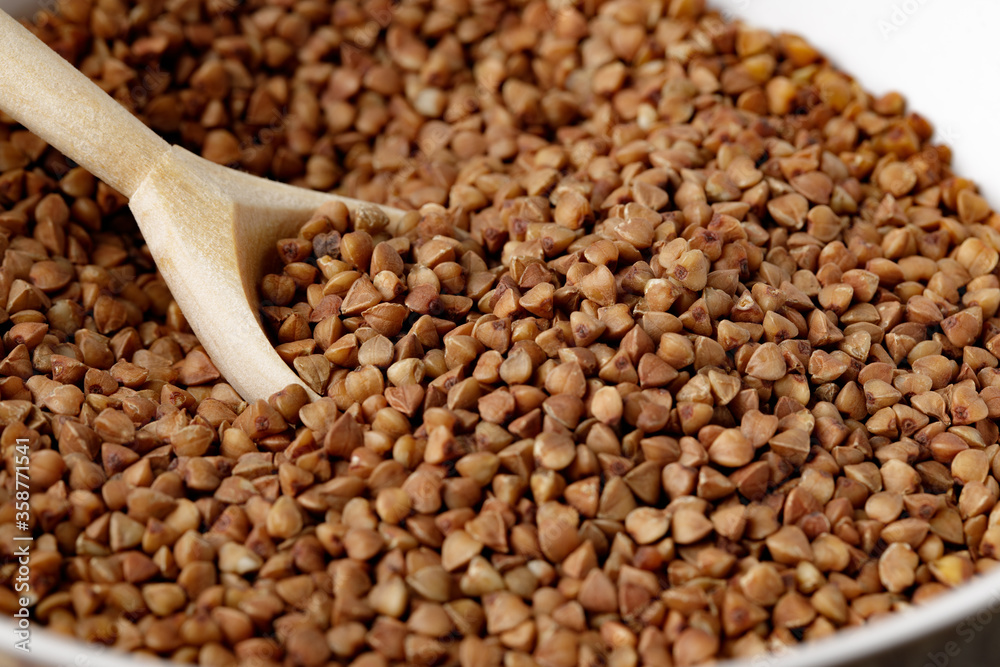 Bowl of raw uncooked buckwheat on wooden table Bowl of raw uncooked buckwheat on wooden table