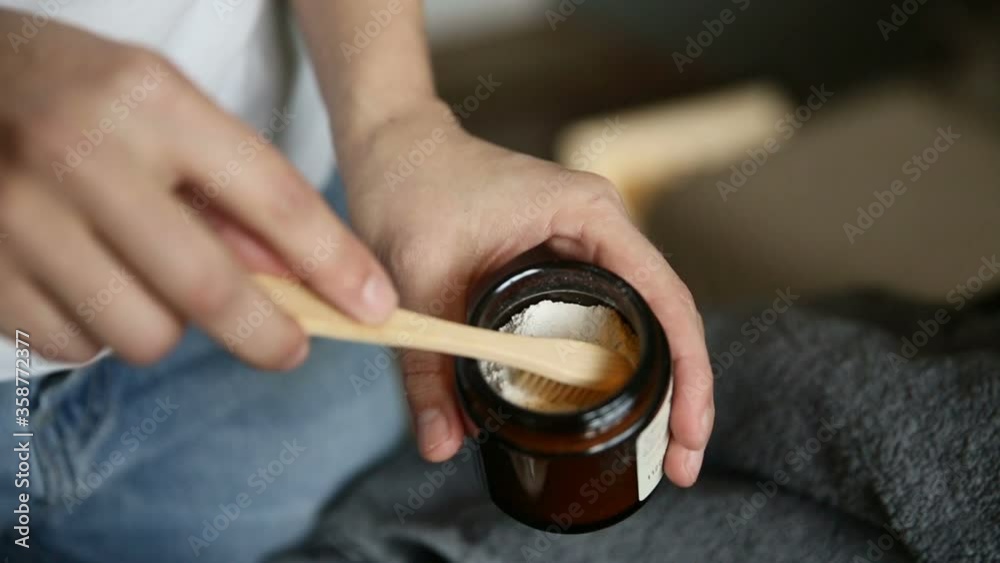 applying dental powder to a wooden toothbrush. iroi person woman hand demonstrating wooden bamboo brush. showing oral hygiene product. concept bio, recycle, conscious. eco friendly toothpowder