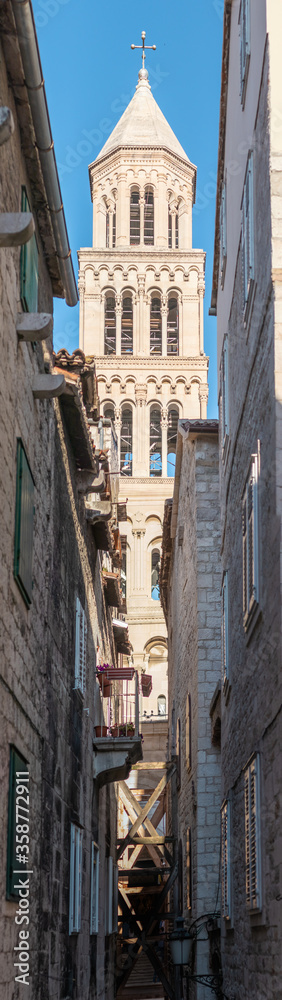 Saint Dominus cathedral belltower seen from a different angle, from inbetween the tiny streets between buildings. Vertical shot stretching far high.