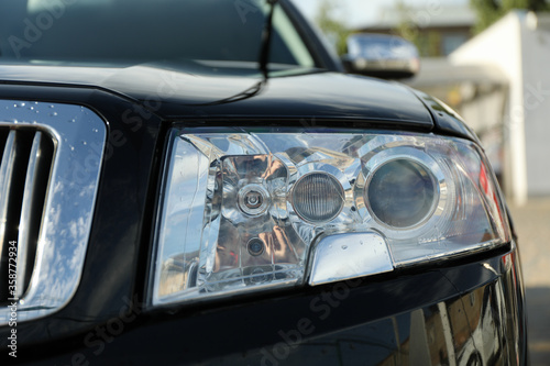   ar headlight of black sedan  close up. Outdoor photo